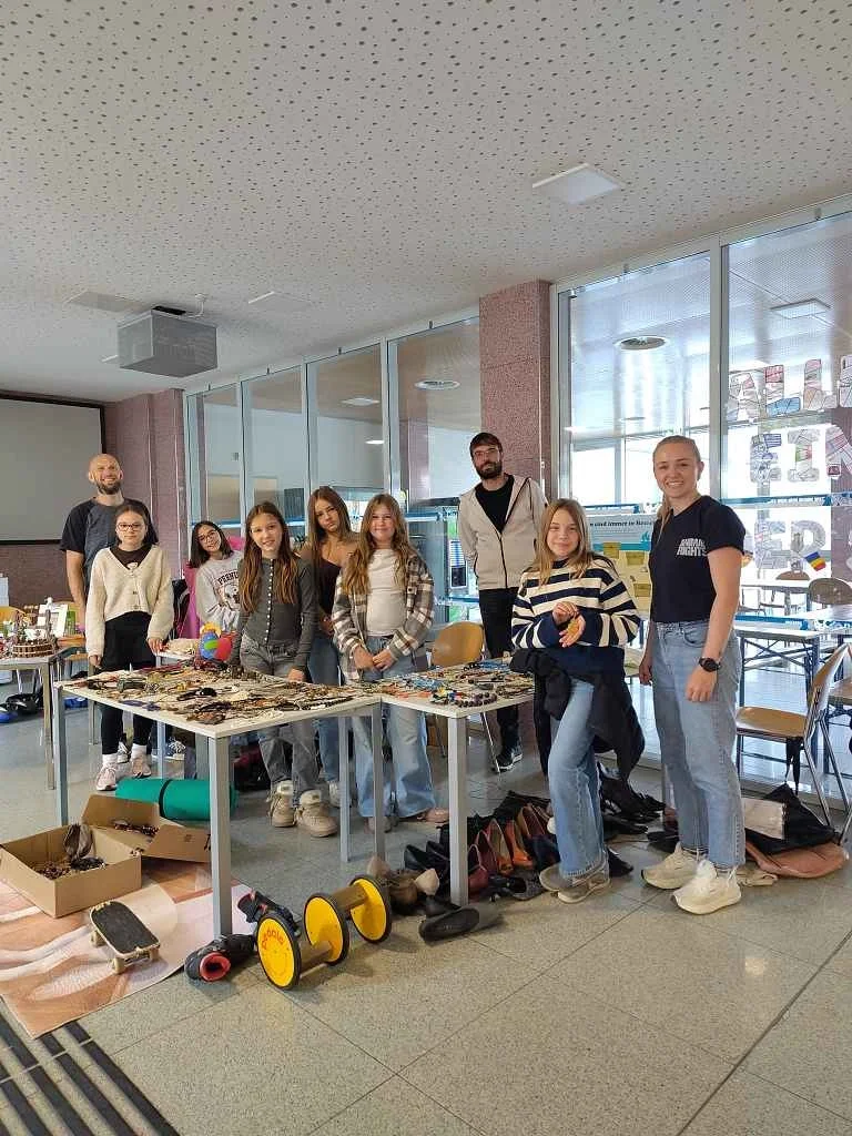 Schülerinnen und Schüler präsentieren Schmuck und Accessoires auf einem Tisch in einem Schulgebäude.